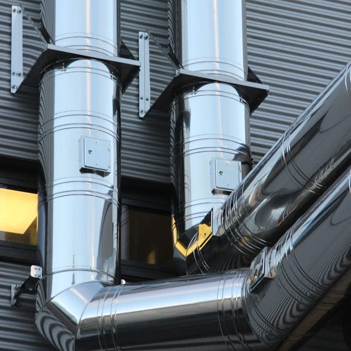 close-up-of-machine-part-in-factory-257770 Close-up of shiny stainless steel pipes on an industrial building facade, showcasing modern technology.