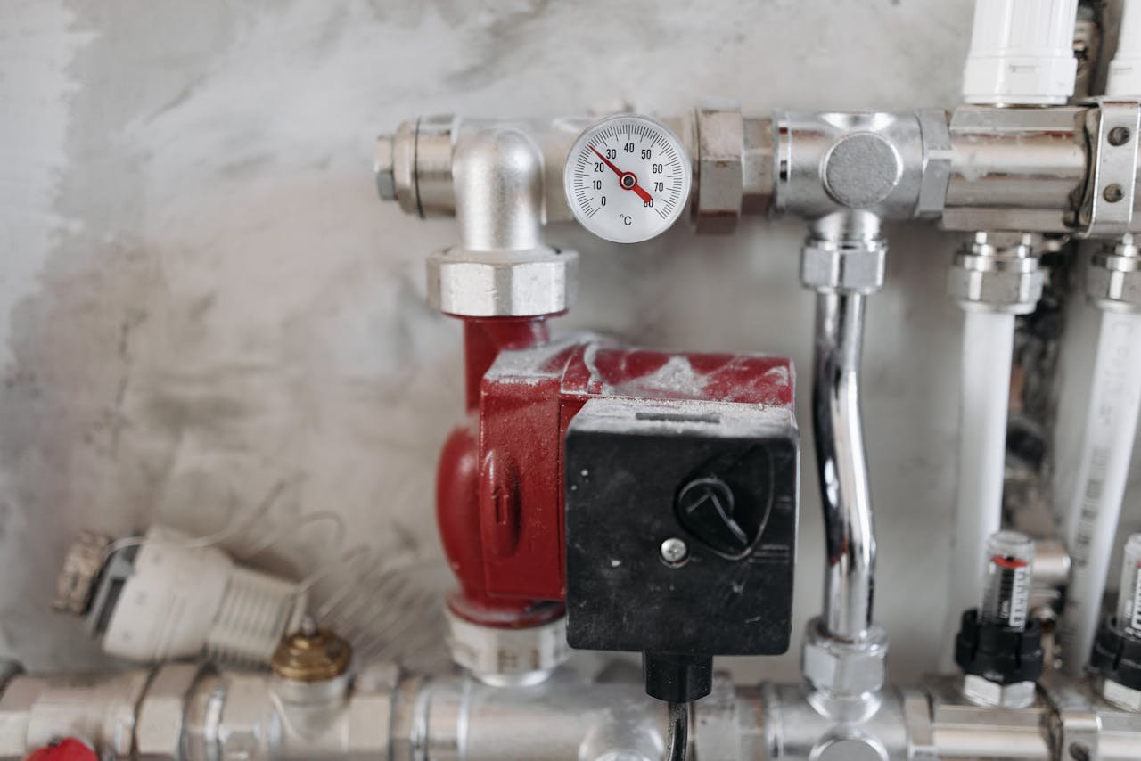 our-story Close-up view of an industrial plumbing system featuring a pressure gauge and steel pipes.