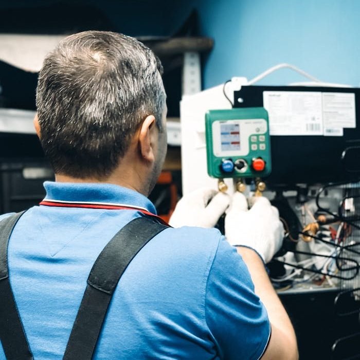 technician-performing-air-conditioning-maintenance-32588555 A skilled technician working on air conditioning system maintenance indoors.